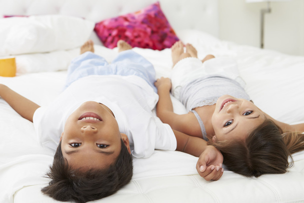 Children Lying Upside Down On Bed In Pajamas Together - Photo, image