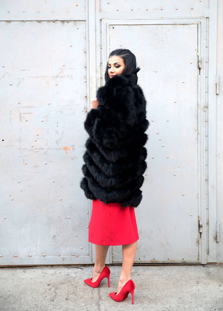 Young beautiful woman in fur coat  posing on city street  - Photo, Image