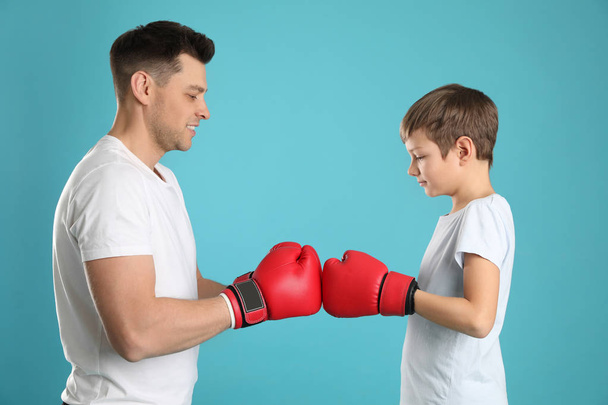 Dad and his son with boxing gloves on color background - Fotografie, Obrázek