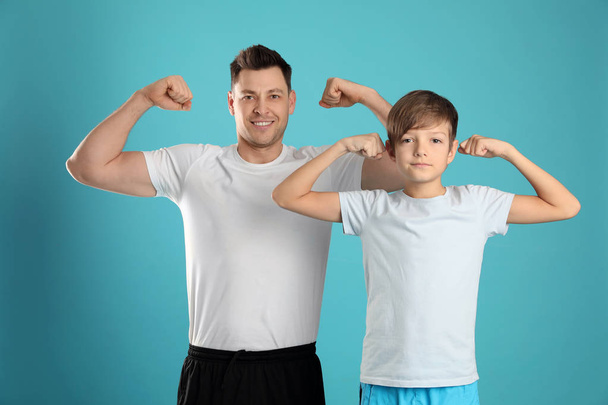 Portrait of sporty dad and his son on color background - Foto, Bild