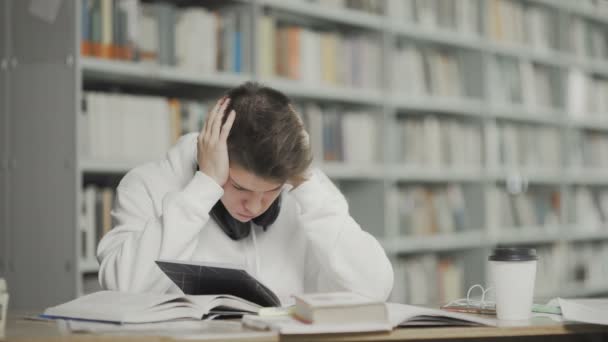 Étudiant fatigué se prépare pour l'examen à la bibliothèque universitaire - Séquence, vidéo
