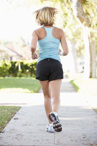 Rear View Of Female Runner Exercising On Suburban Street - Foto, imagen
