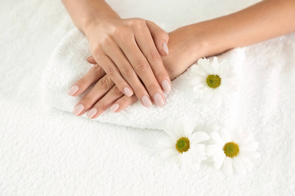 Woman with smooth hands and flowers on towel, closeup. Spa treatment - Photo, Image