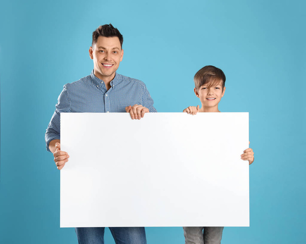 Dad and his son with empty banner on color background. Space for design - Valokuva, kuva