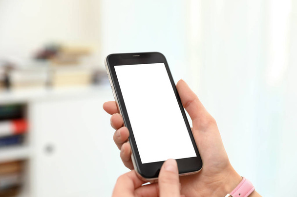 Woman holding smartphone with blank screen indoors, closeup of hands. Space for text - Valokuva, kuva