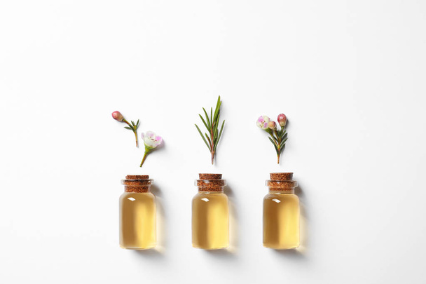 Flat lay composition with bottles of natural tea tree oil on white background - Fotó, kép