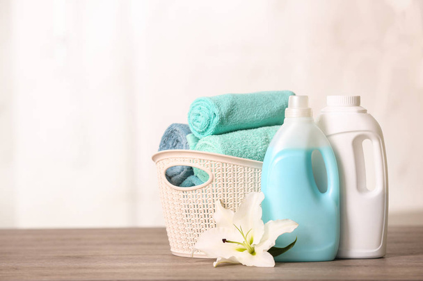 Limpie las toallas en la cesta con lirio y detergentes en la mesa. Espacio para texto
 - Foto, imagen