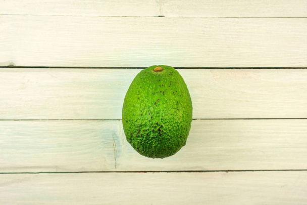 Avocado close-up. whole avocado on bright wooden table - Фото, зображення