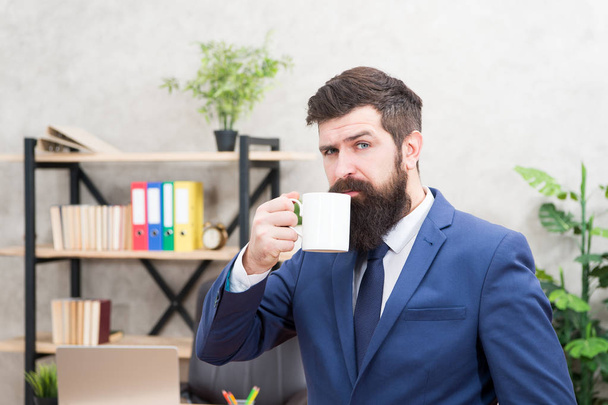 Man bearded businessman hold coffee cup stand office background. Start day with coffee. Successful people drink coffee. Drinking coffee relaxing break. Boss enjoying energy drink. Caffeine addicted - Foto, Imagem
