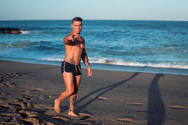 Tatuato bodybuilder sexy allenatore maschile in spiaggia
. - Foto, immagini