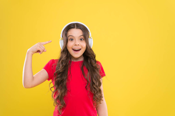 Music to your ears. Adorable child listen to music playing in earphones on yellow background. Little girl enjoying her favorite music. Cute small kid listening to music in headset, copy space - Фото, зображення