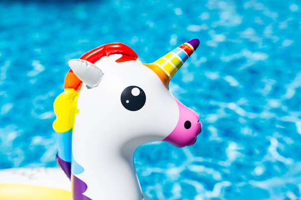 Inflatable colorful white unicorn at the swimming pool. Summer time in the swimming pool with plastic toys. Summer vacation, Relaxation and fun concept - Фото, изображение