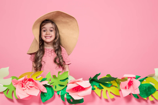 ピンクの背景に夏の帽子をかぶった少女の肖像画 - 写真・画像