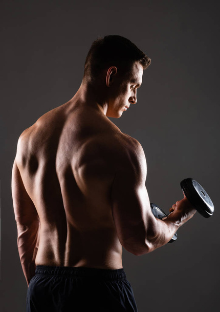 Strong, fit and sporty bodybuilder man with dumbbell over black background. Sport and fitness concept. - Φωτογραφία, εικόνα