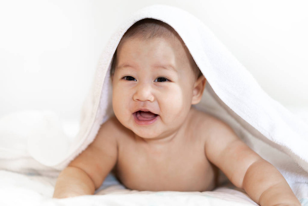 Retrato de la sonrisa feliz bebé relajándose bajo la toalla después del baño en
  - Foto, imagen