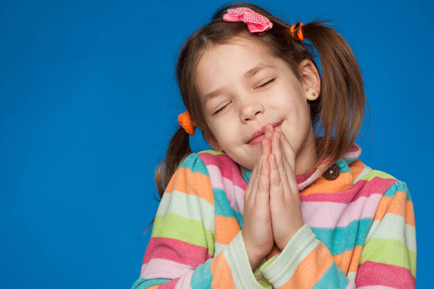 Πορτραίτο ενός συναισθηματικού κοριτσιού πέντε χρόνων με ριγέ πουλόβερ σε μπλε φόντο - Φωτογραφία, εικόνα