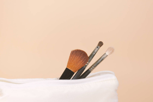 Three cosmetic brushes are sticking out of a white bag - Photo, Image