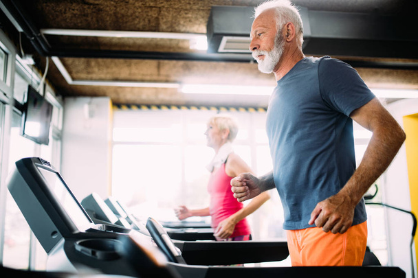 Mature people running on a treadmill in health club. - Fotó, kép