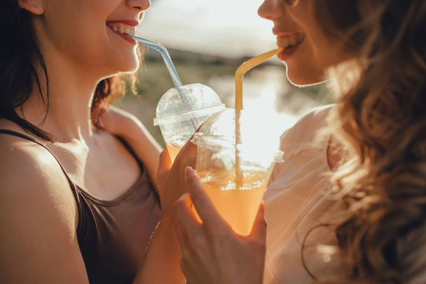 közelről. az öröm fogalma: két csinos lány barátaival inni koktél, szórakozni a nyáron, a naplemente, a pozitív arckifejezés, kültéri - Fotó, kép