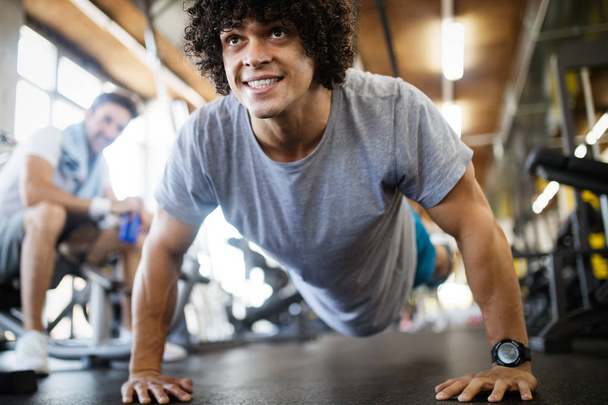 Portrait of a handsome man doing push ups exercise in fitness gym - Foto, imagen