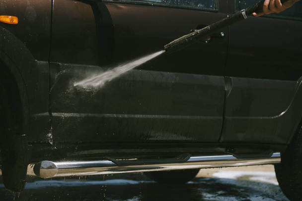 A man washes a car with a high pressure washer - Fotó, kép