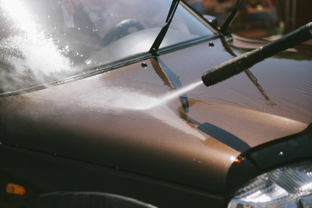 Egy ember mossa az autót egy nagynyomású mosó - Fotó, kép