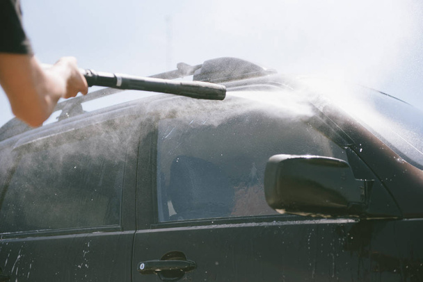 A man washes a car with a high pressure washer - Foto, afbeelding