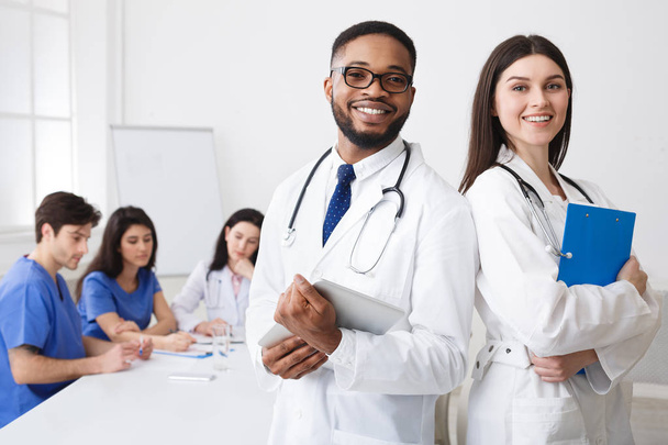 Diverse professionele artsen in witte jassen poseren voor camera op - Foto, afbeelding