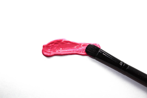Lápiz labial líquido rosa manchado, rubor líquido aislado sobre fondo blanco. Cepillo para maquillar. Concepto de maquillaje y belleza
. - Foto, imagen