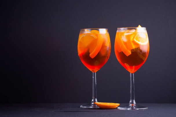 Cocktail aperol spritz on black background. Summer alcohol cocktail with orange fruit and fresh mint. Italian cocktail aperol spritz on wooden boards - Foto, Imagem