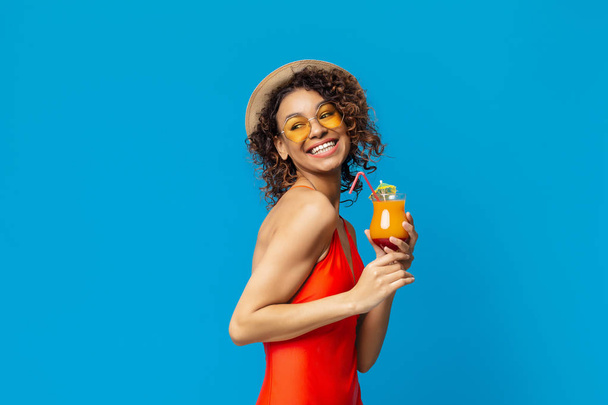 Cheerful african american woman in swimsuit drinking summer cocktail - Photo, Image