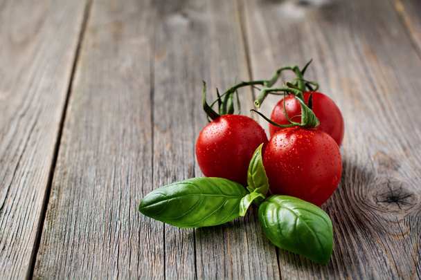 Fresh Tomato cherry branch of basil on old wooden background. Selective focus. - Zdjęcie, obraz