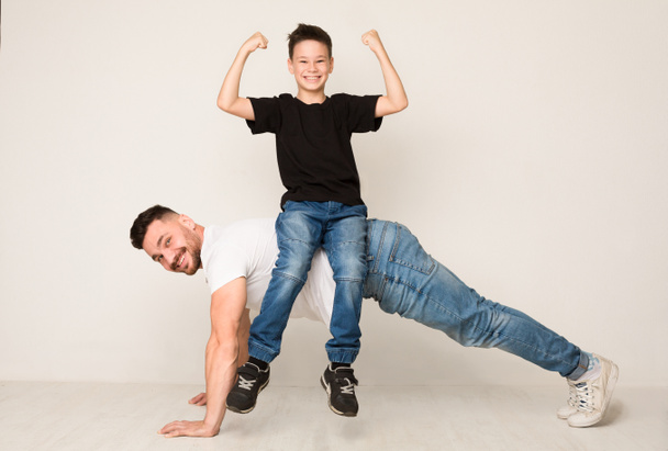 Vader doet push-ups met zoon op rug - Foto, afbeelding