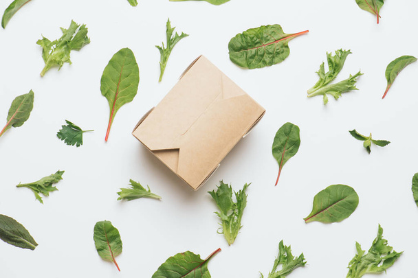 Hot food paper box over vegetable abstract background, made of salad leaves - 写真・画像