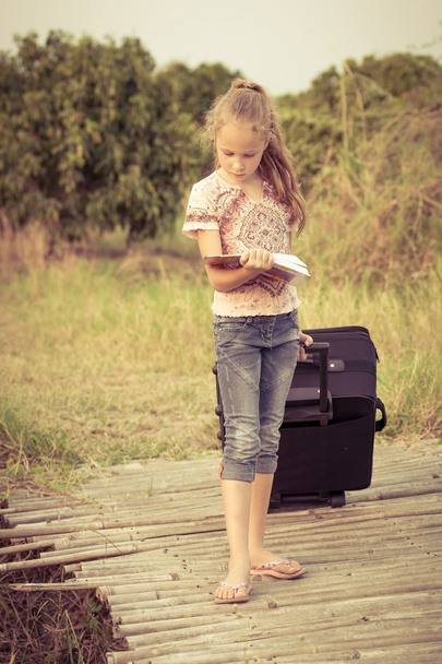 Little girl standing and reading a book on nature - Foto, Bild