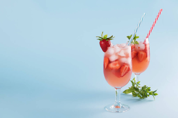 Fresh strawberry summer cocktail and ice cubes. Two glasses with strawberry, ice and wine - strawberry sangria on a pastel blue backgound, minimalism - Photo, Image