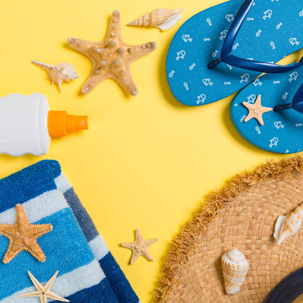 flip flops, straw hat, starfish, sunscreen bottle, body lotion spray on yellow background top view . flat lay summer beach sea accessories background, holiday concept - Photo, Image