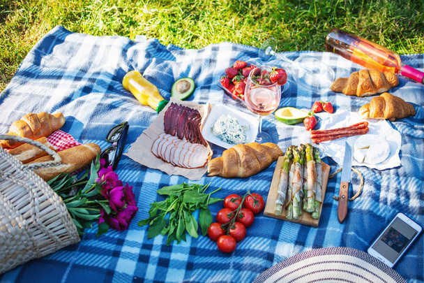 Letni piknik w parku na trawie. Wino, owoce i rogaliki - Zdjęcie, obraz