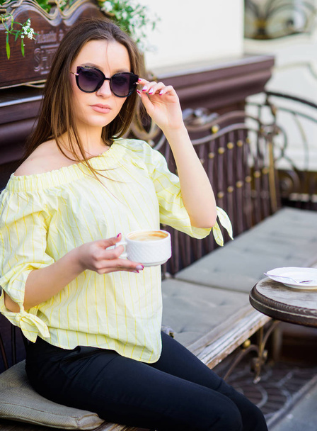 Breakfast time in cafe. Girl enjoy morning coffee. Woman in sunglasses drink coffee outdoors. Girl relax in cafe cappuccino cup. Caffeine dose. Coffee for energetic successful day. Waiting for date - Fotoğraf, Görsel