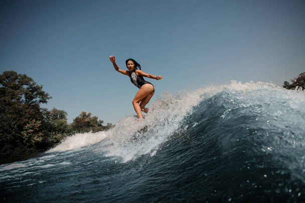 Brunette woman surfs on surfboard in sea - Fotó, kép