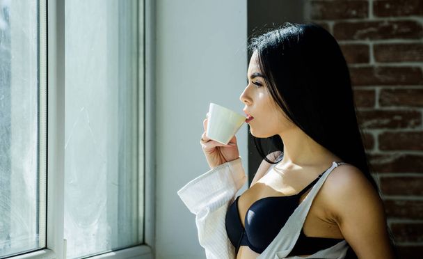 A reggeli bőséges és finom. Imádnivaló nő kávét iszik reggelire. Érzéki lány élvezi reggeli italt az ablakon. Reggeli ital recept Jumpstart minden reggel - Fotó, kép