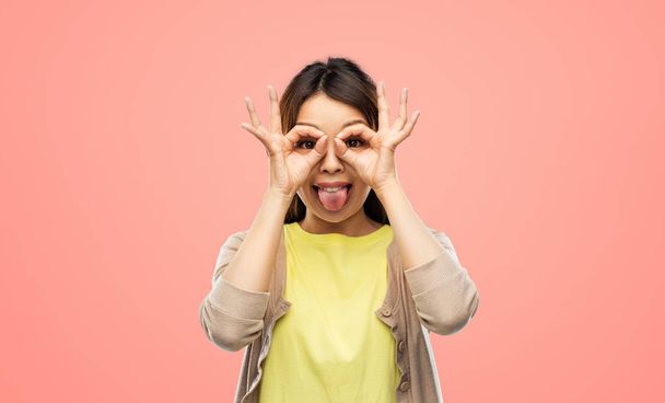 smiling asian woman looking through finger glasses - Fotó, kép