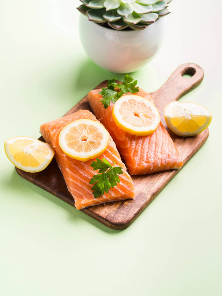 Filete de salmón sobre tabla de madera con rodajas de limón
 - Foto, Imagen