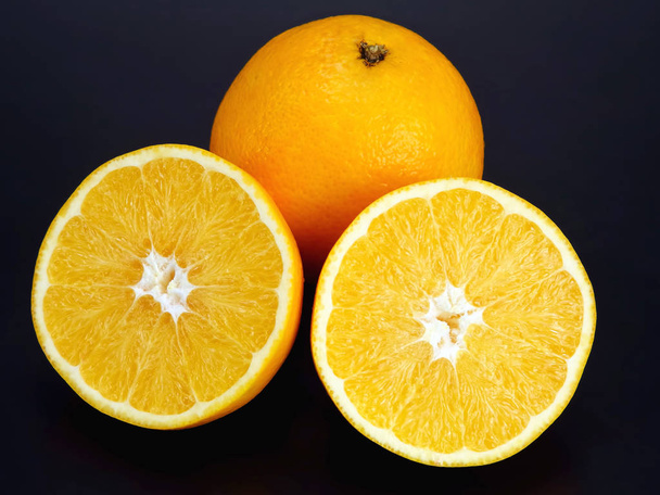 Citrus fruit. Cut and whole orange on dark background - Fotografie, Obrázek