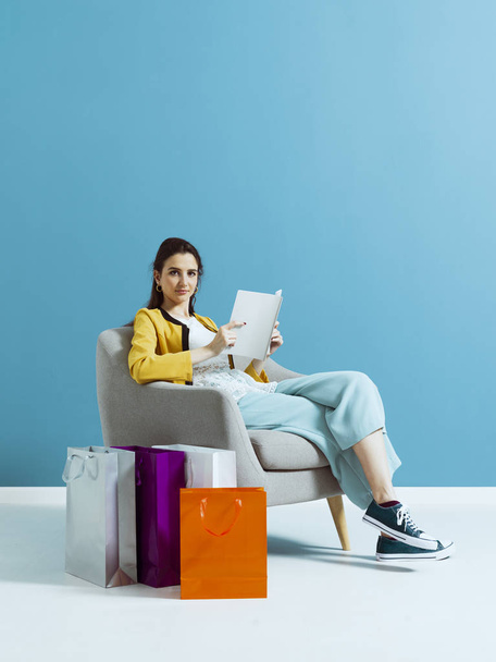 Woman shopping and reading a fashion magazine - Фото, зображення