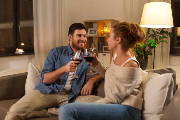 happy couple drinking red wine at home in evening - Zdjęcie, obraz