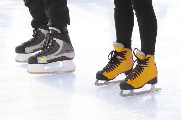Füße verschiedener Menschen, die auf der Eisbahn Schlittschuh laufen - Foto, Bild