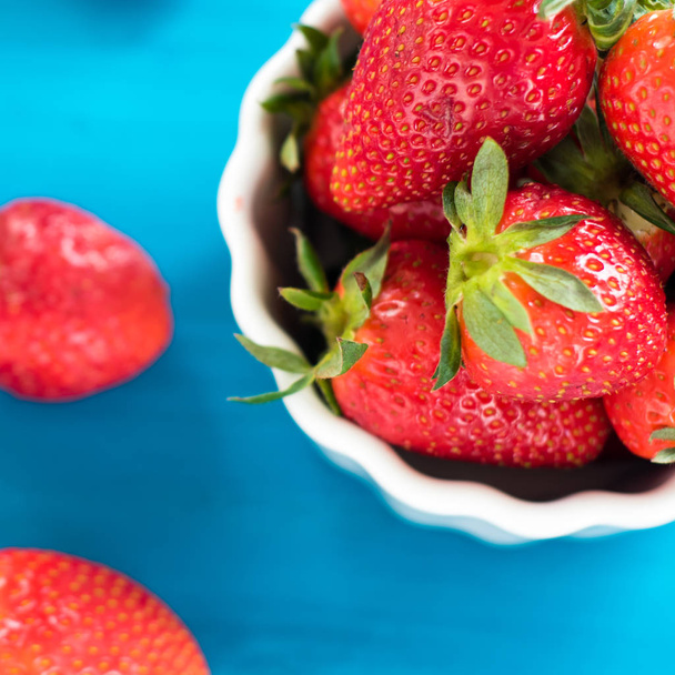 fresh bright strawberries in a bowl top view on a blue background - Фото, зображення