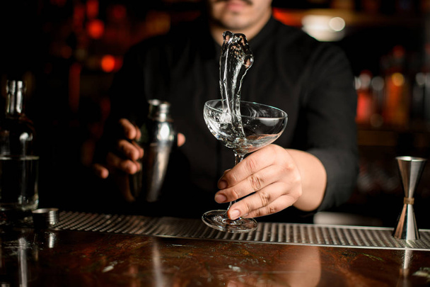 Bartender making a splash of the transparent alcohol in the cocktail glass - Foto, imagen