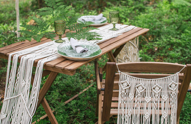 Στυλ Μπόχο γαμήλια δεξίωση τραπέζι με τραπεζομάντιλο μακραμέ, διακόσμηση σε ένα ρουστίκ ξύλινο τραπέζι - Φωτογραφία, εικόνα